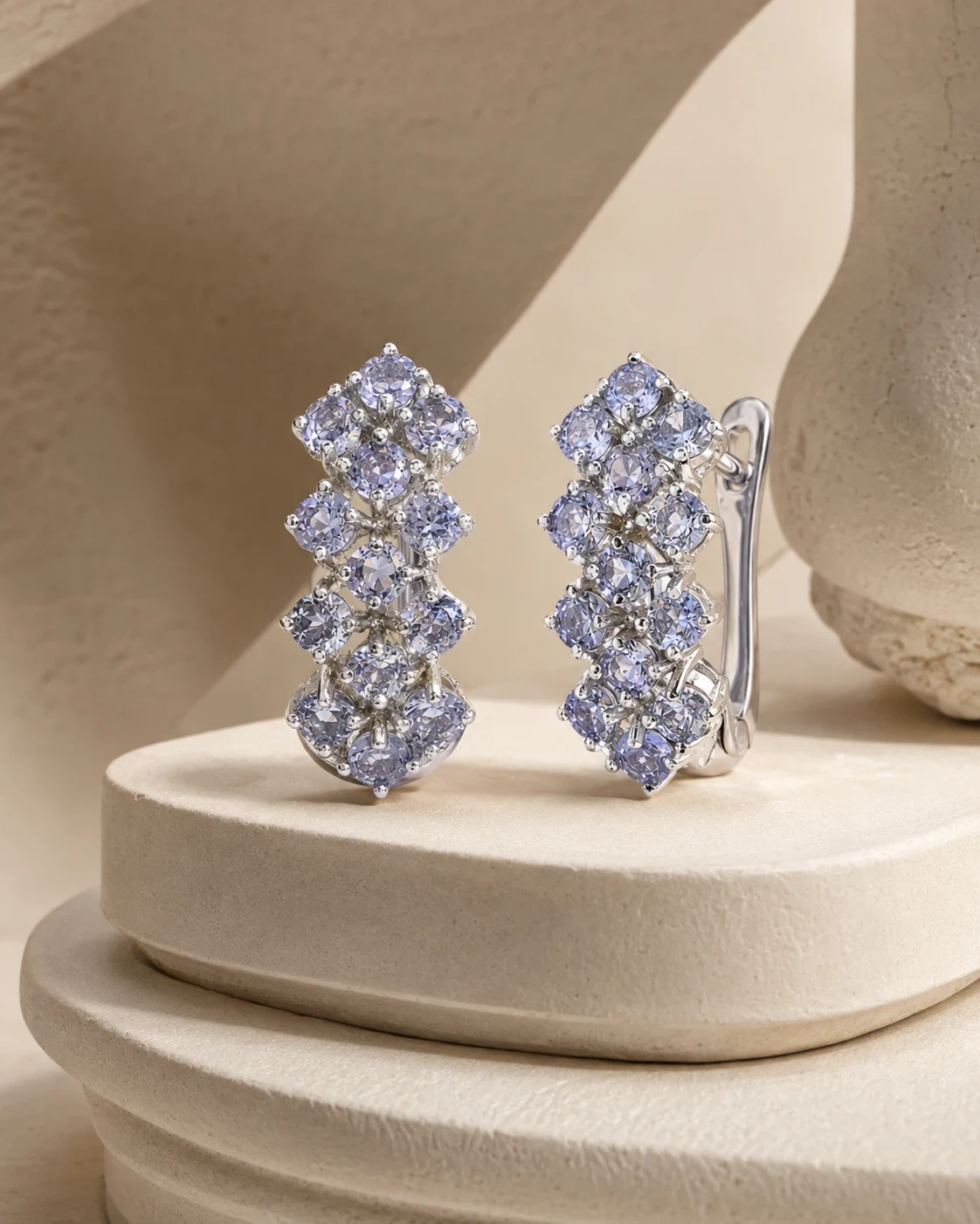 The pair seen close, showing the four staggered clusters of round stones and the hinged clip fitting behind.